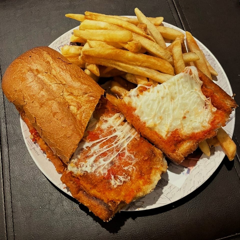 A Viva Italiano Pizzeria chicken parmesan sub with melted cheese and a side of golden french fries.