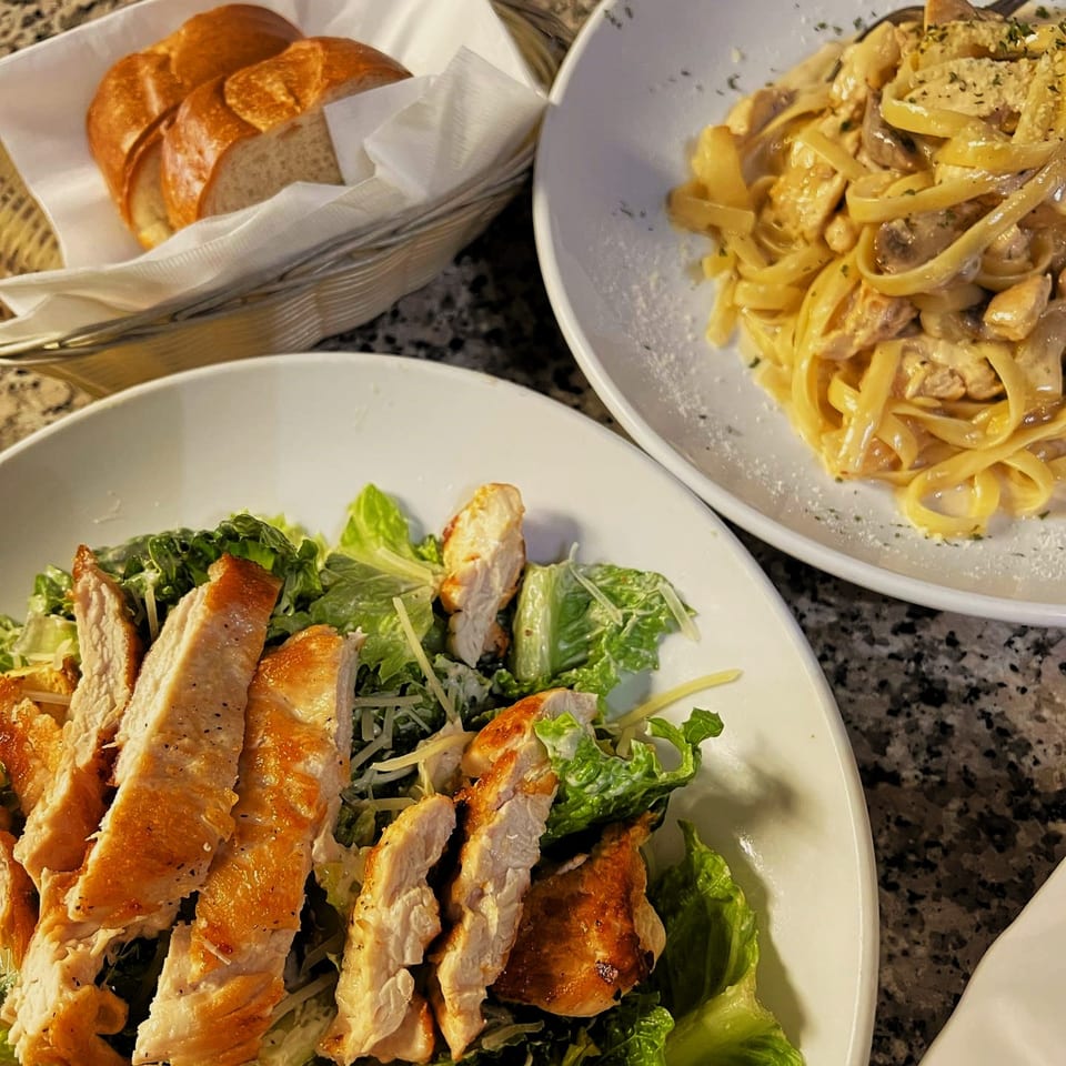 Viva Italiano Pizzeria's chicken Caesar salad, fettuccine alfredo with mushrooms, and a bread basket.